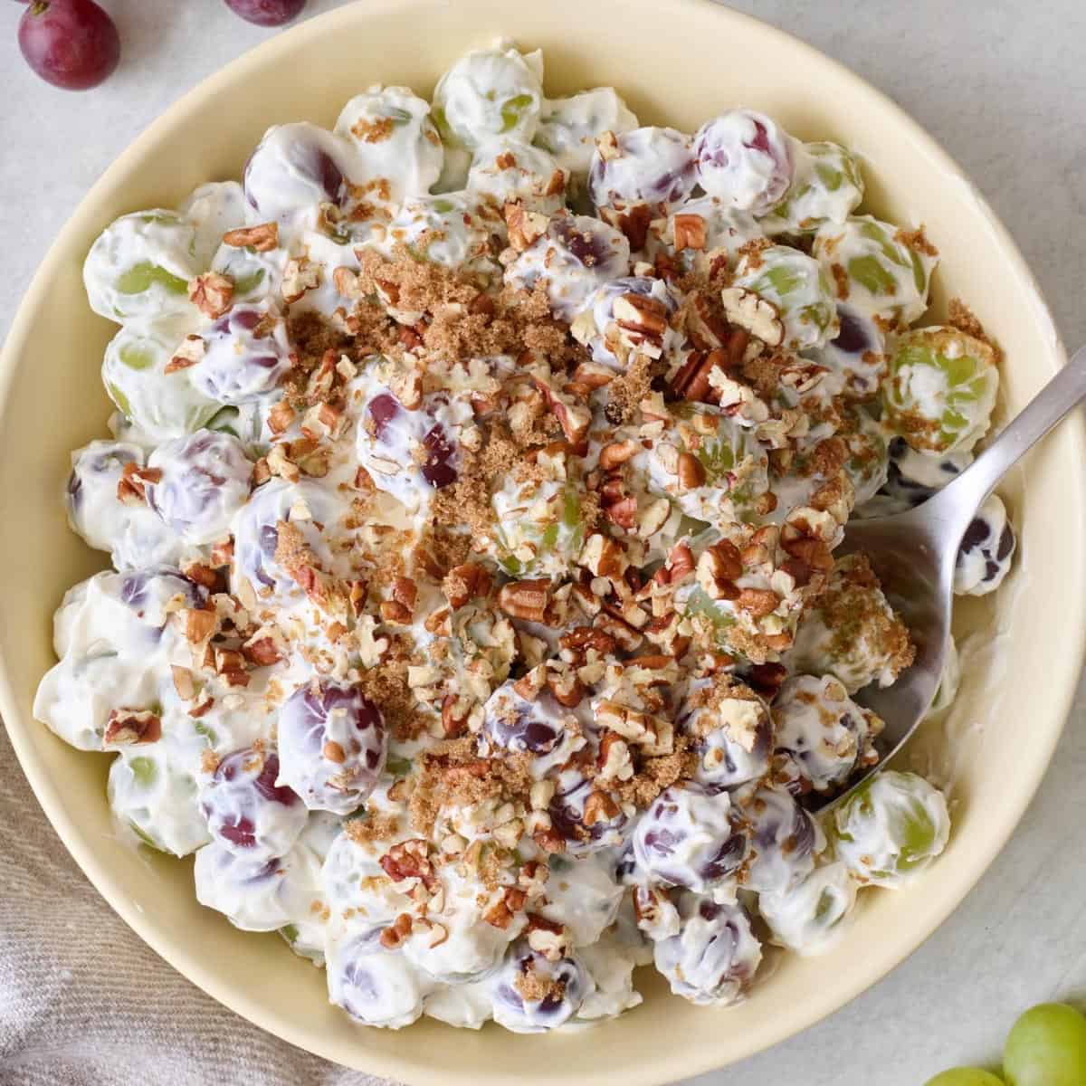Closeup of grape salad in a bowl with chopped pecans.