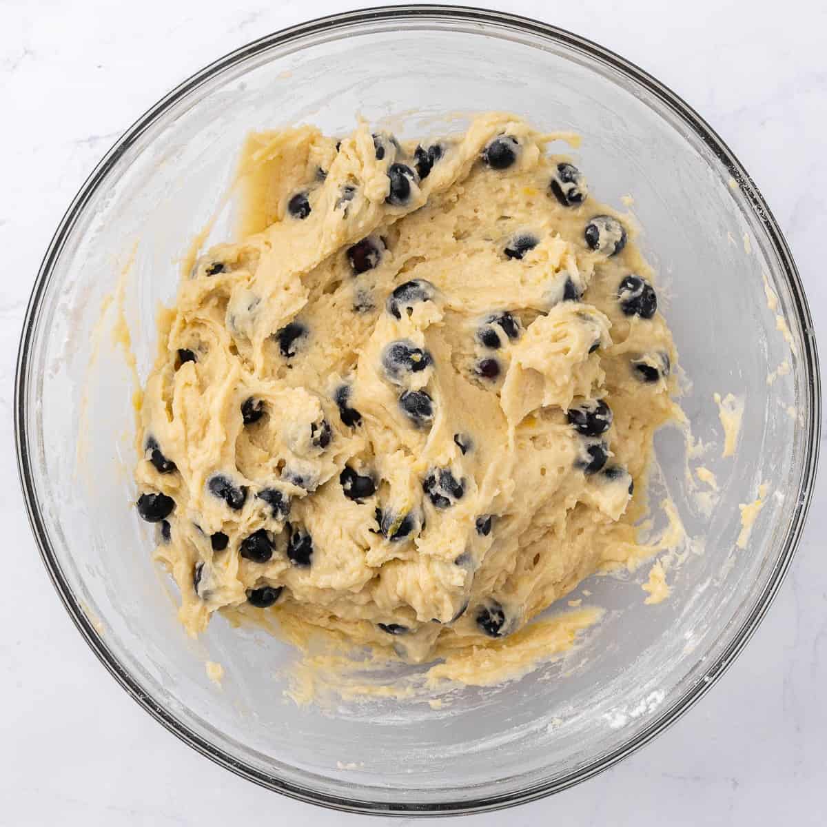 Lemon blueberry muffin batter in a large glass mixing bowl.