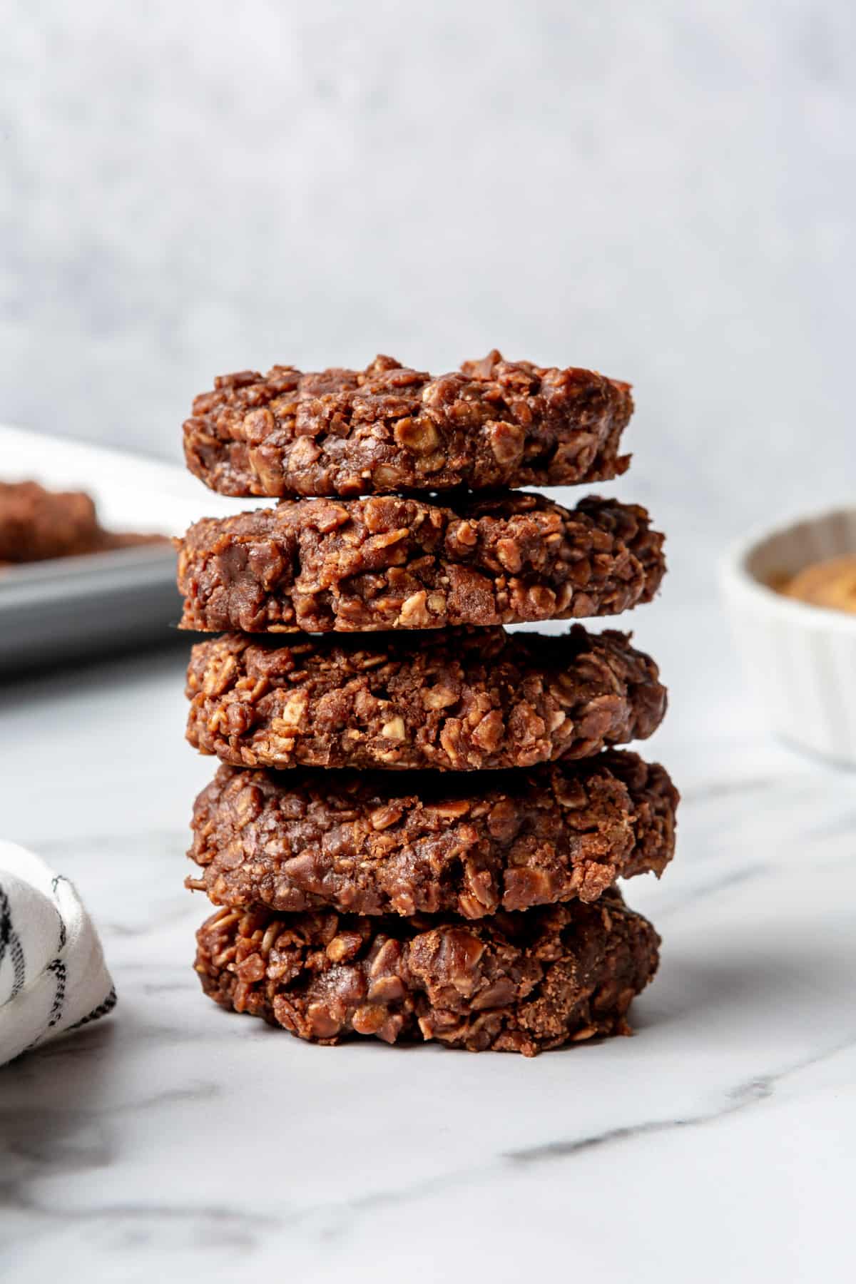 Stack of no-bake oatmeal cookies on marble countertop.