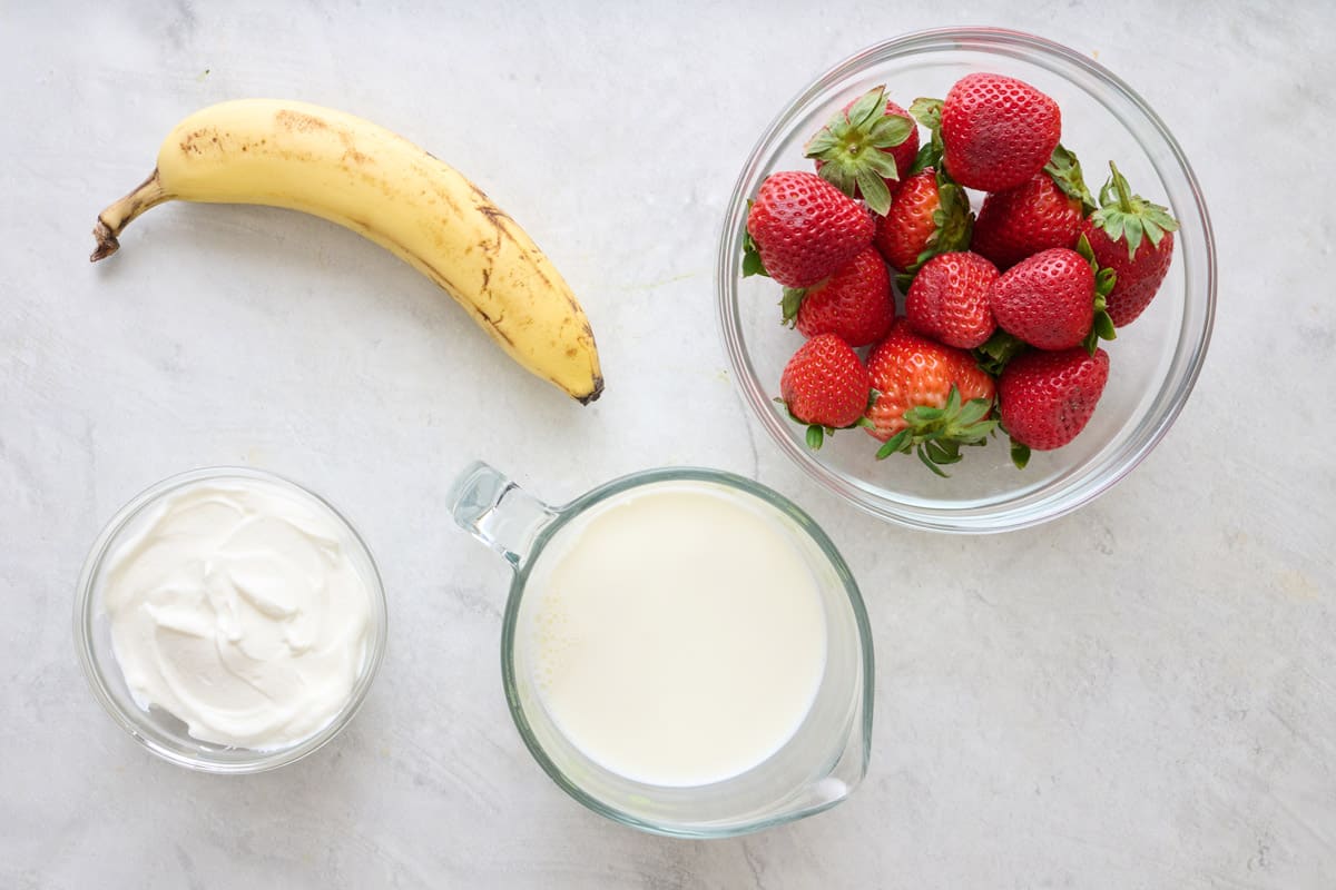 Ingredients for recipe before prepping: banana yogurt, milk, and strawberries.