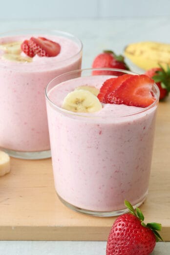 Strawberry banana smoothie in two small glasses with extra strawberry and banana slices on top.