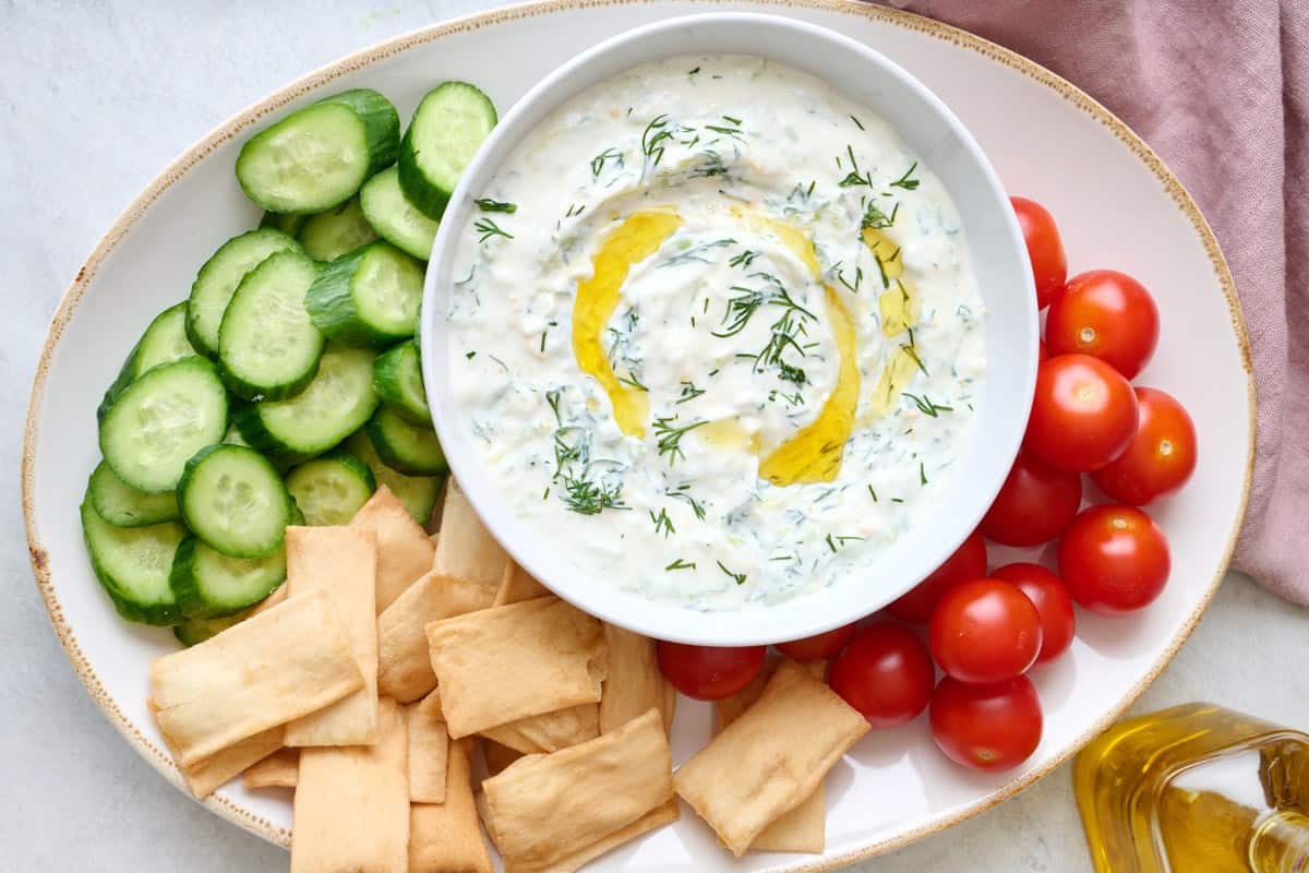 Tzatziki sauce in a bowl rested on a platter of vegetables.
