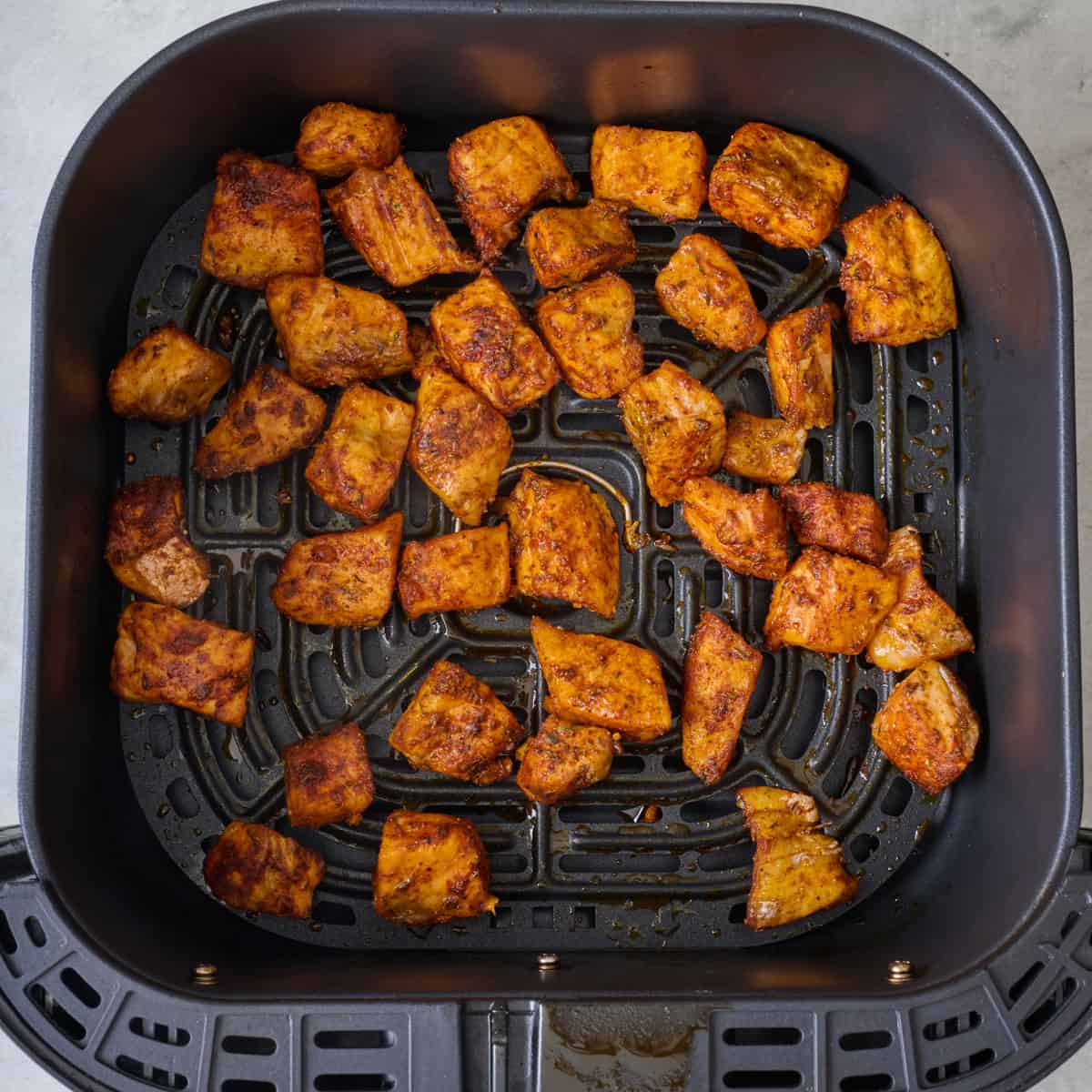 Fish bites after air frying in an air fryer basket.