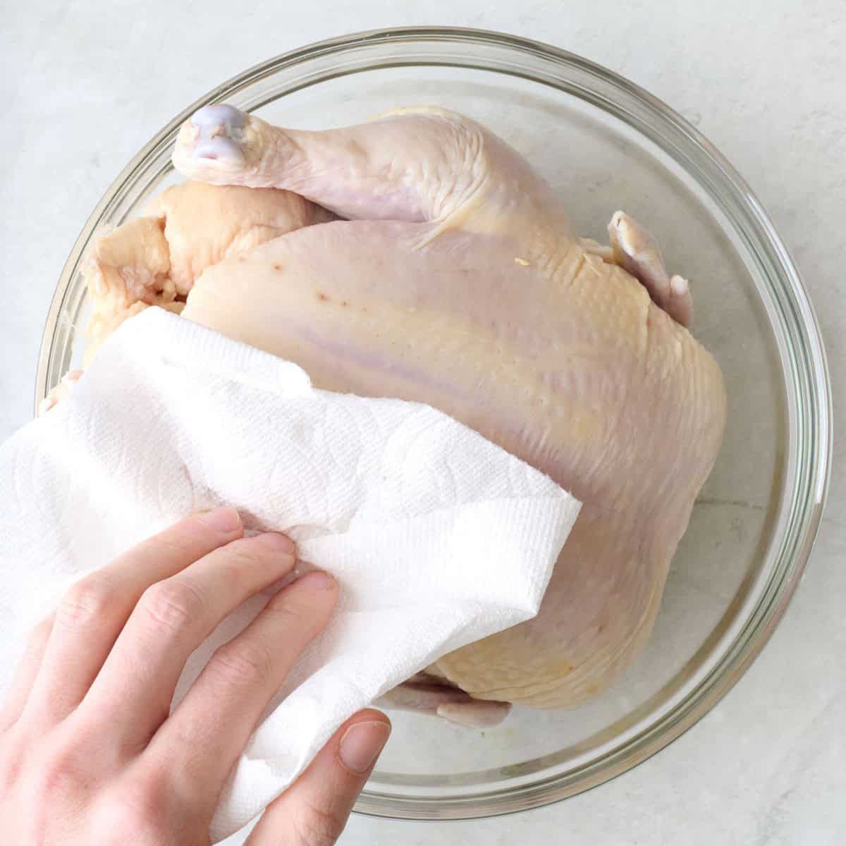 Patting chicken dry with a paper towel.