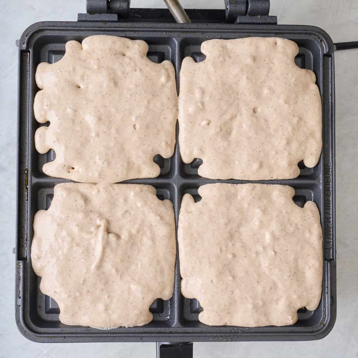 Waffle batter added to a hot waffle iron before cooking.