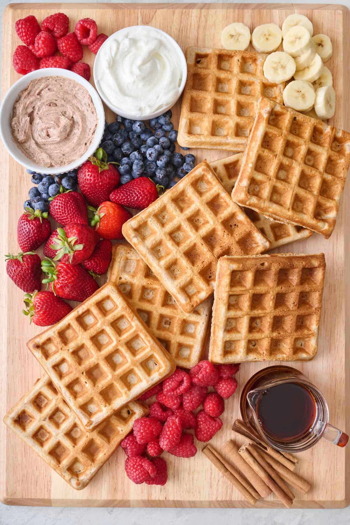 Waffle breakfast board with fresh fruit, whipped cinnamon butter, Greek yogurt, and maple syrup.