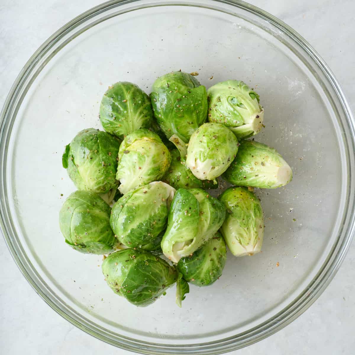 Brussel sprouts in a bowl with oil and spices.