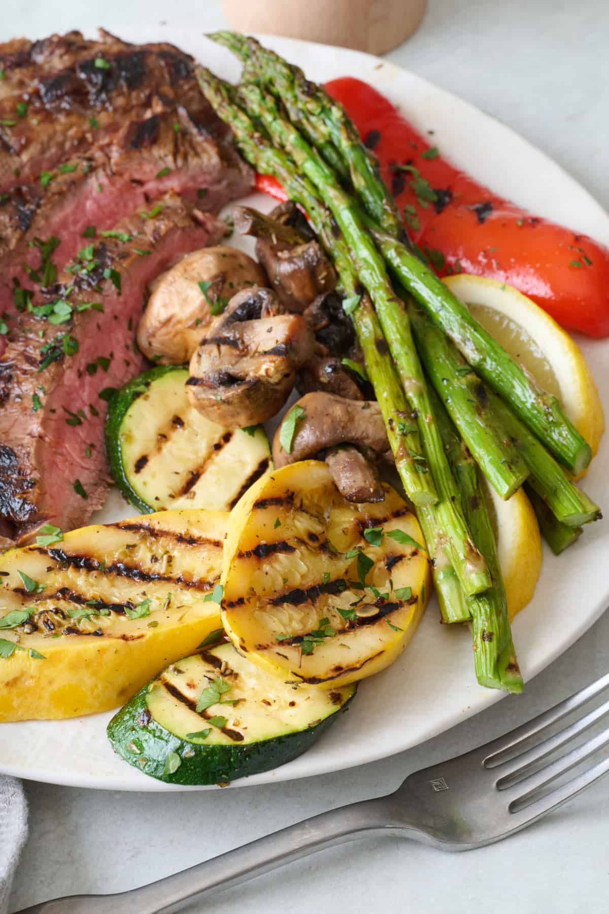 Dinner plate with grilled vegetables and sliced steak.
