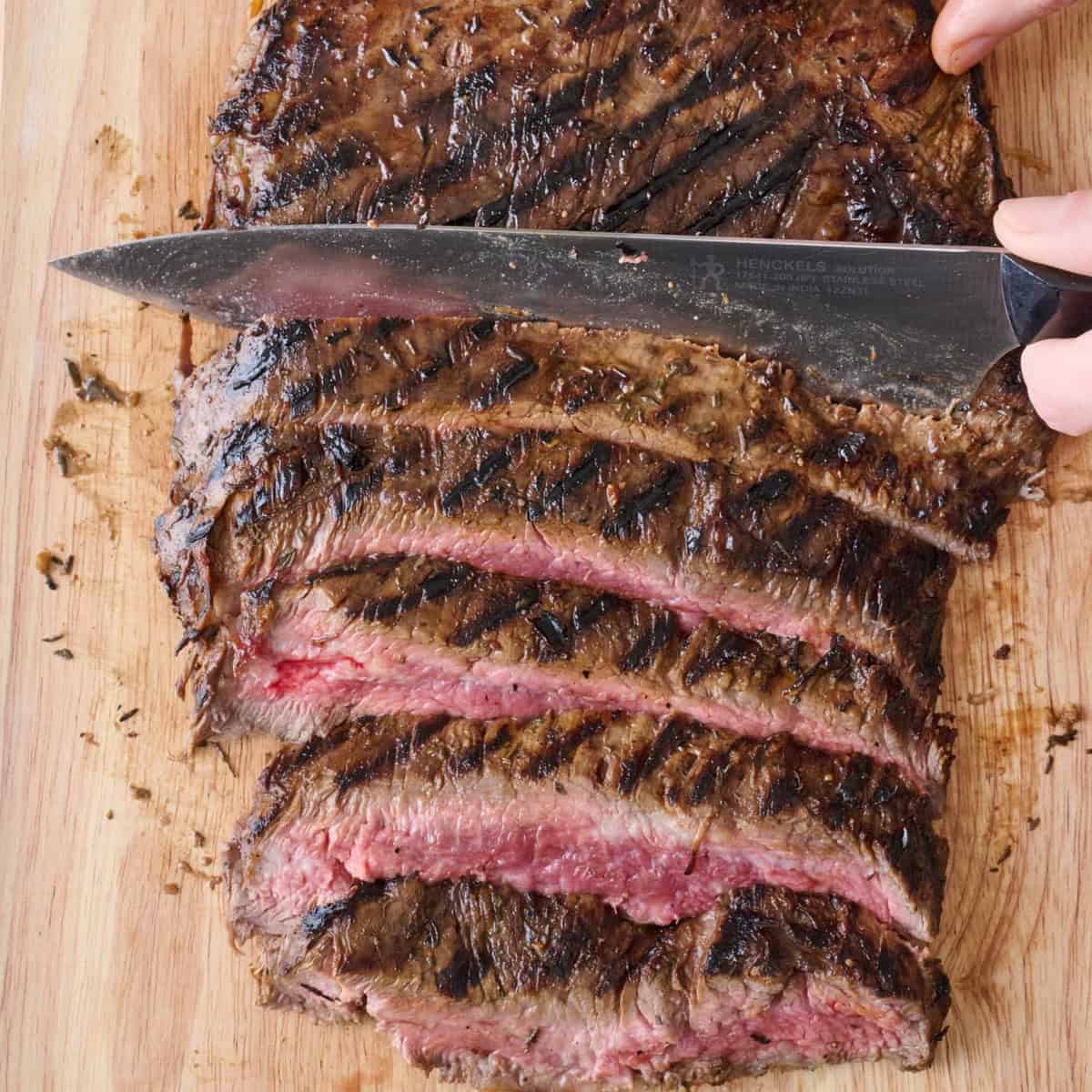 Knife continuing to cut steak into thick strips.