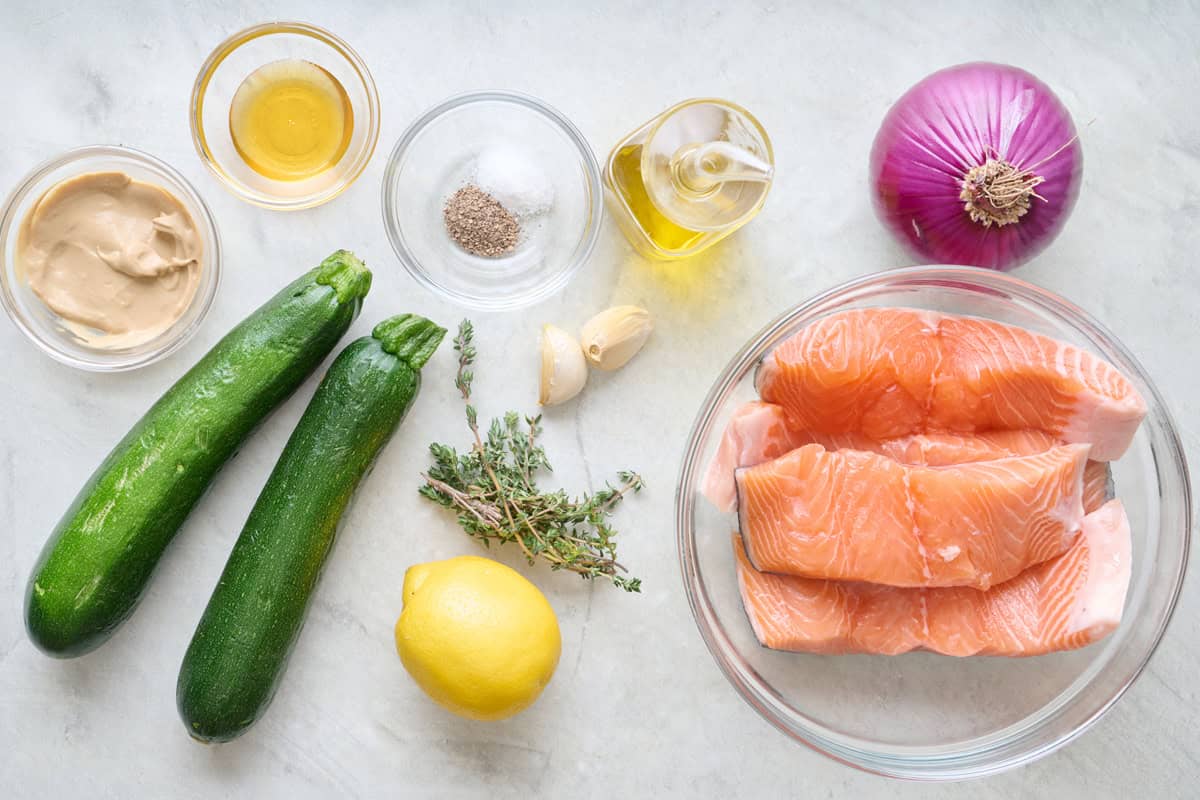 Ingredients for recipe: Dijon mustard, honey, salt and pepper, oil, garlic cloves, fresh thyme, lemon, zucchini red onion, and salmon filets.