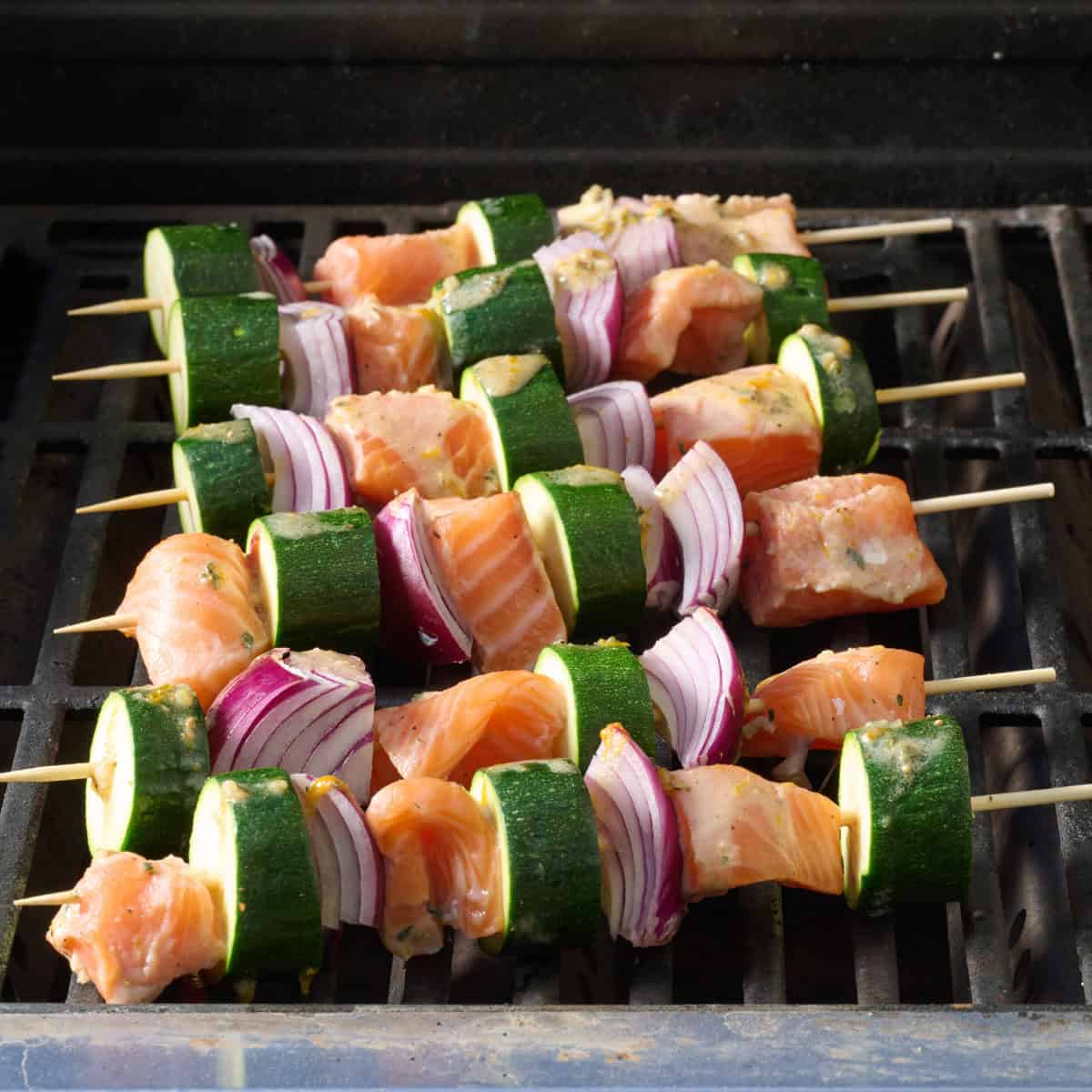 Fish skewers with veggies on a grill before cooking.