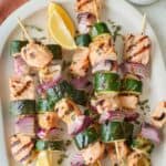 Salmon kabobs with red onions and zucchini slices.