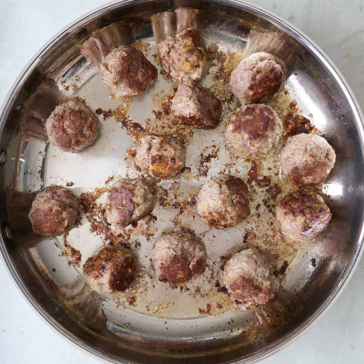 Meatballs in a skillet after browning.