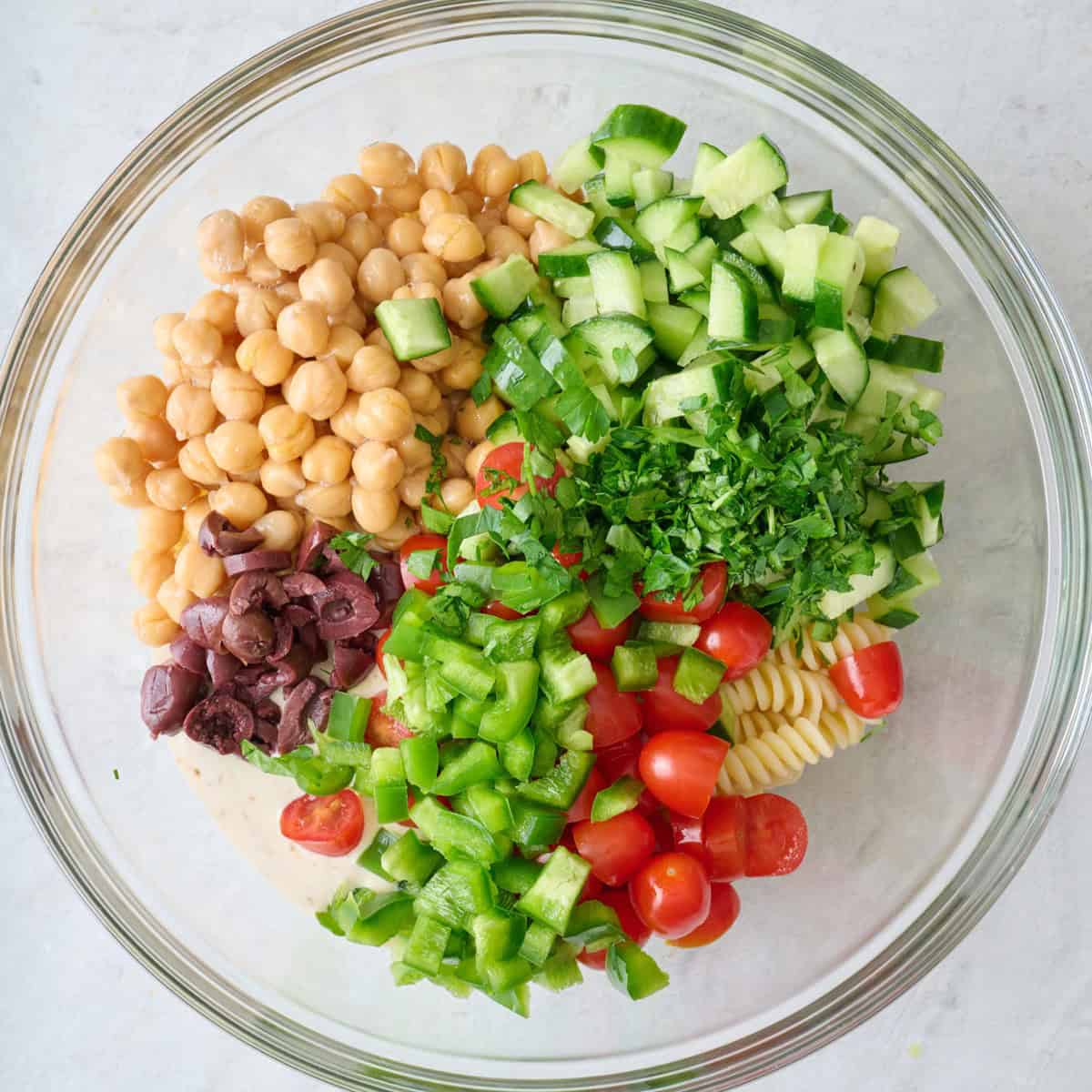 The rest of the pasta salad ingredients added to the bowl.