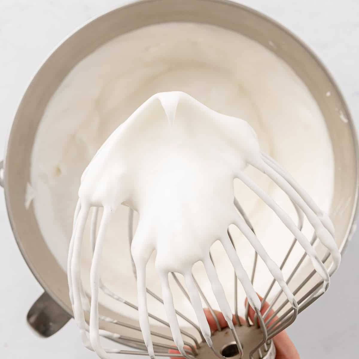 Whisk held above the bowl of batter to show consistency.