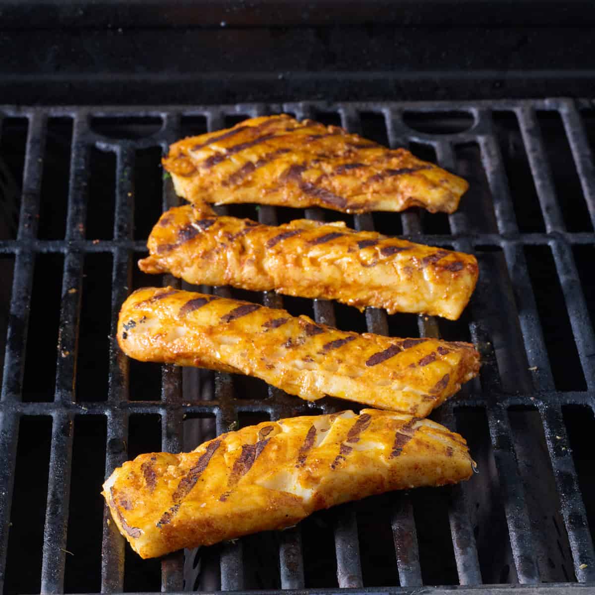 Fish fillets cooking on a gas grill.