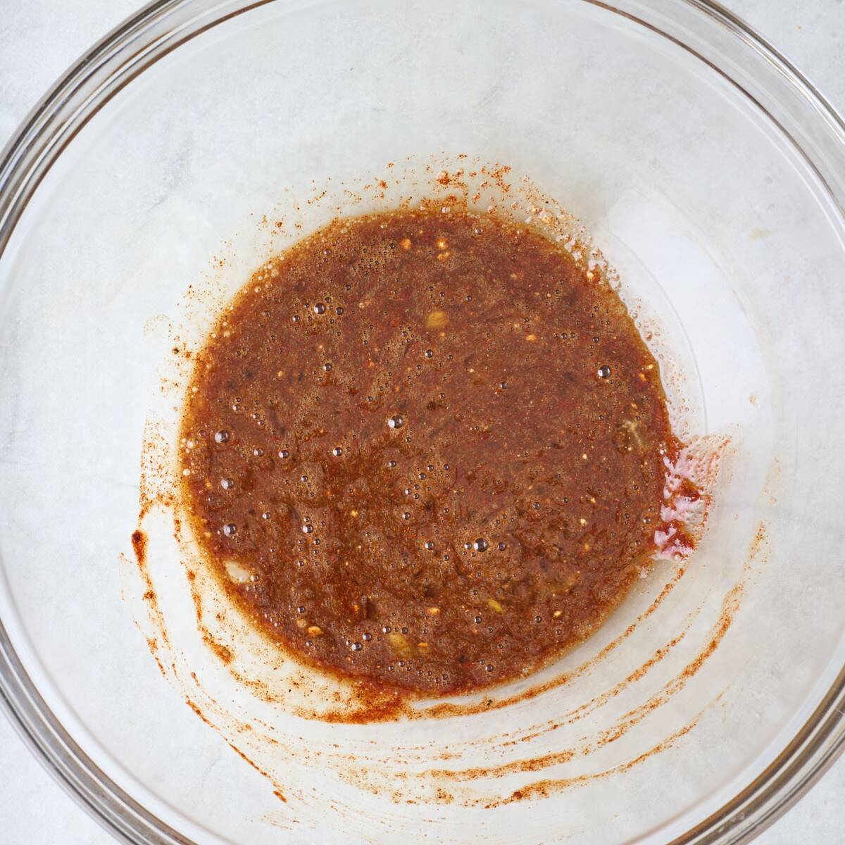 Worcestershire sauce, spices, and an egg mixed together in a mixing bowl.