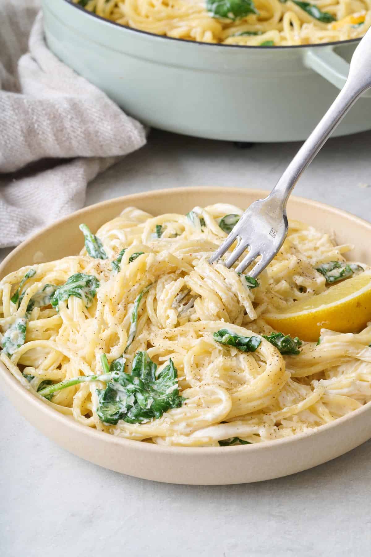 A fork twirling lemon ricotta pasta in a bowl.