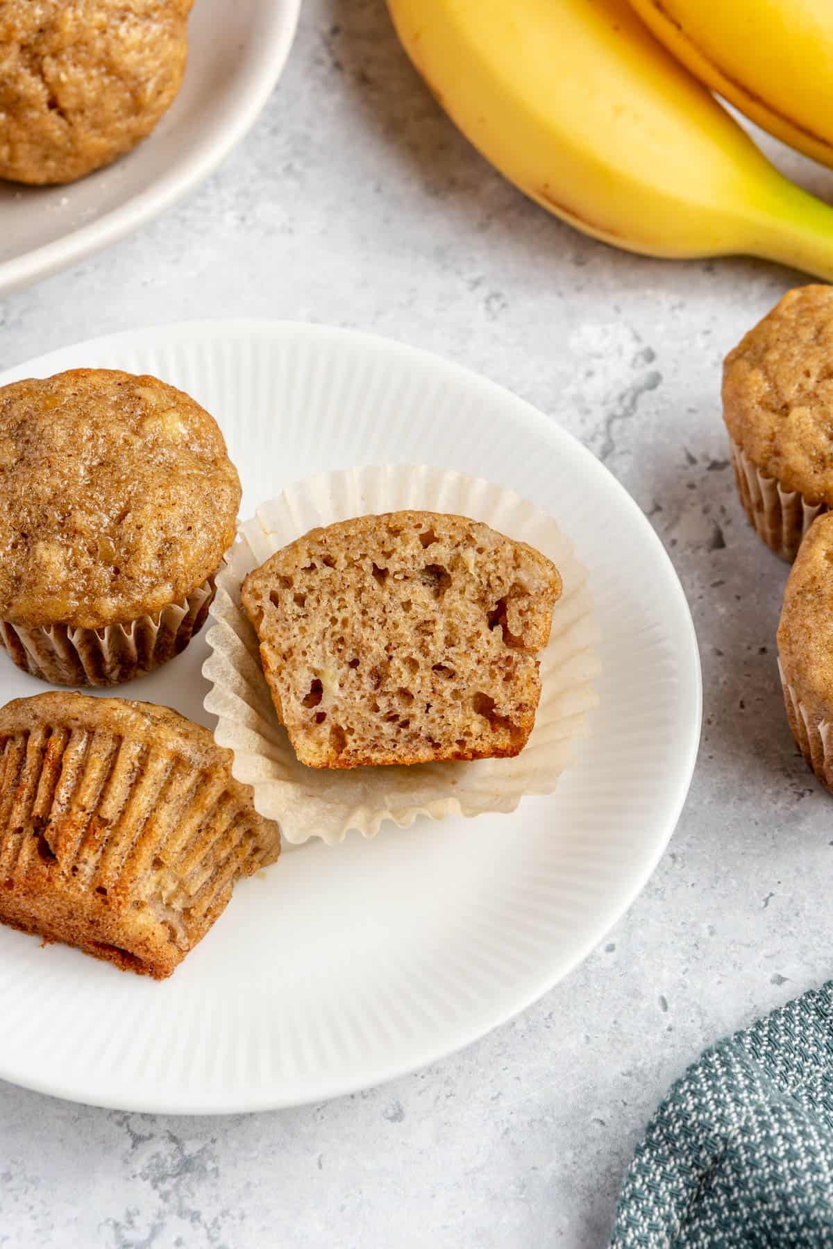 Halved and whole mini banana muffins on a plate.