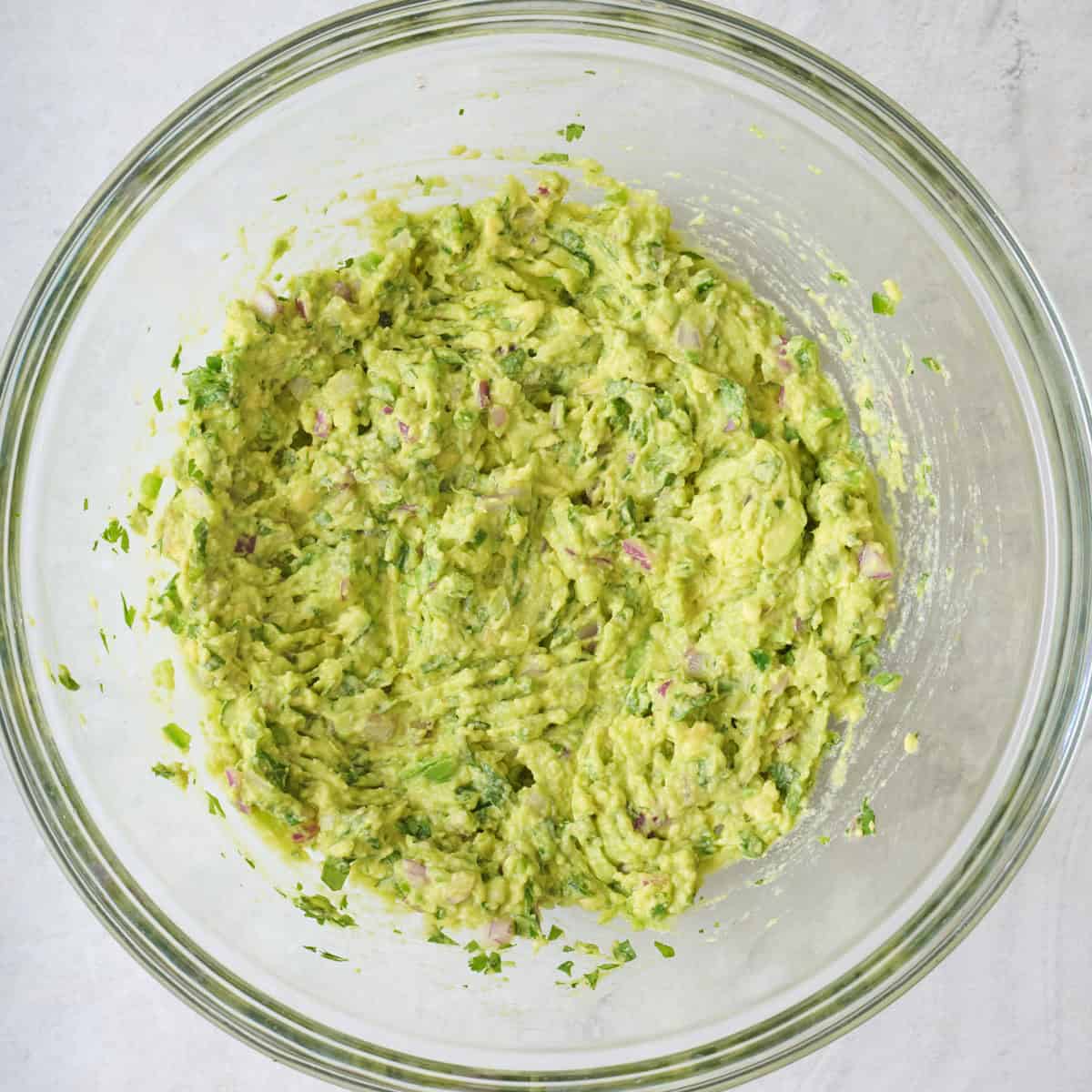 Guacamole in a large glass mixing bowl.