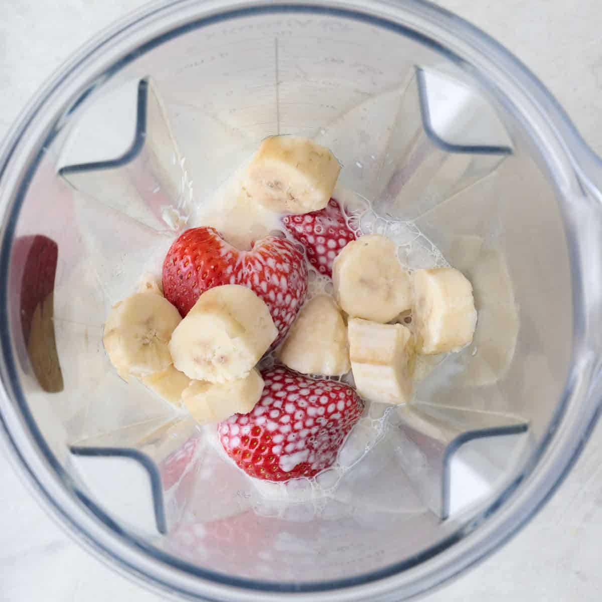 Strawberry banana smoothie ingredients in a blender before blending.