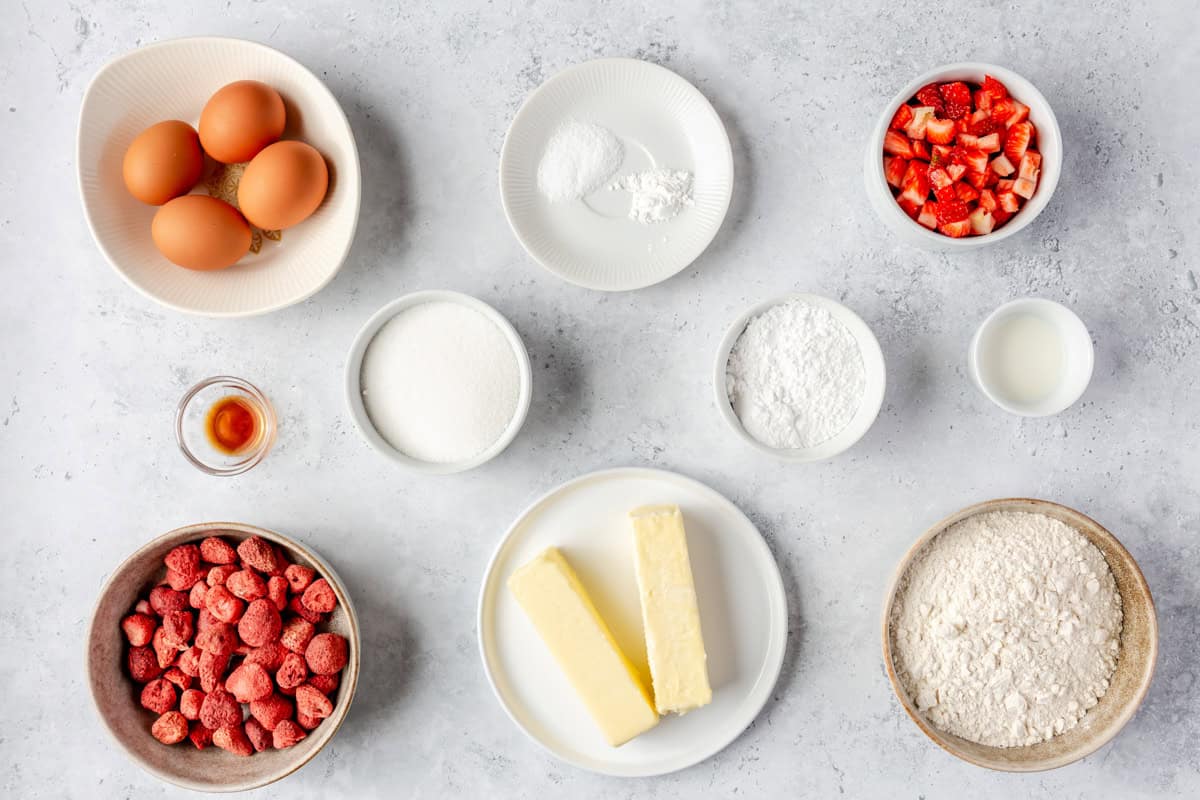 Ingredients for strawberry pound cake, including eggs, butter, chopped strawberries, freeze-dried berries, and flour.