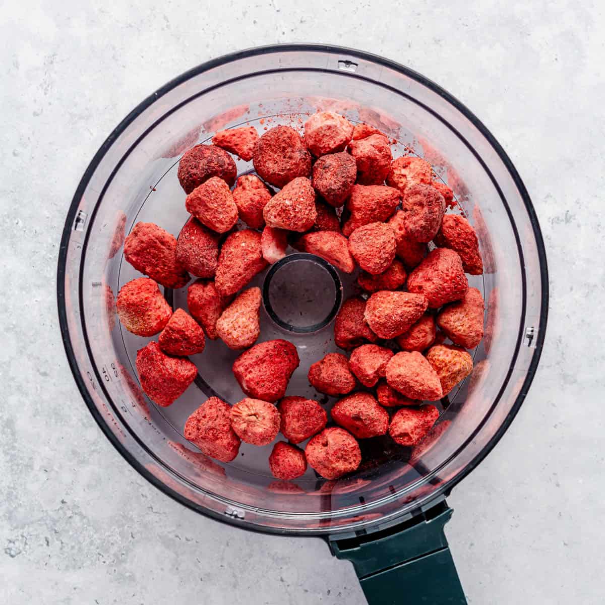 Freeze-dried strawberries in the bowl of a food processor.