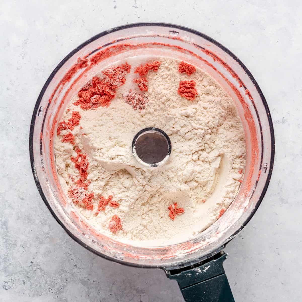 Freeze-dried strawberries, flour, baking powder, and salt in the bowl of a food processor.