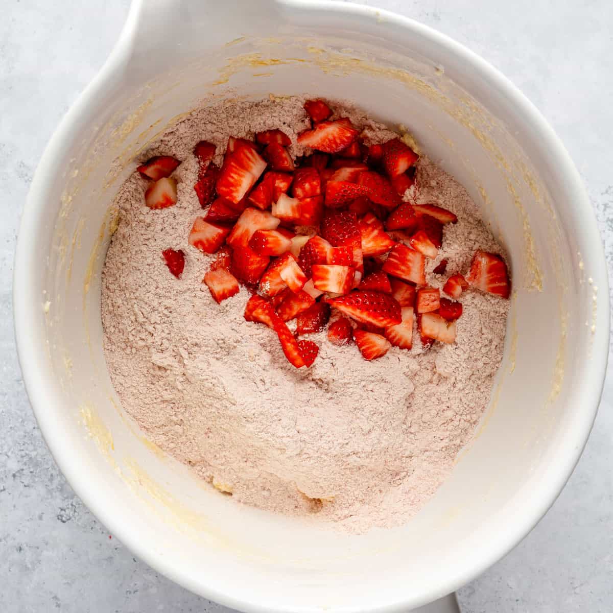 Diced, fresh strawberries and a flour mixture in a mixing bowl.