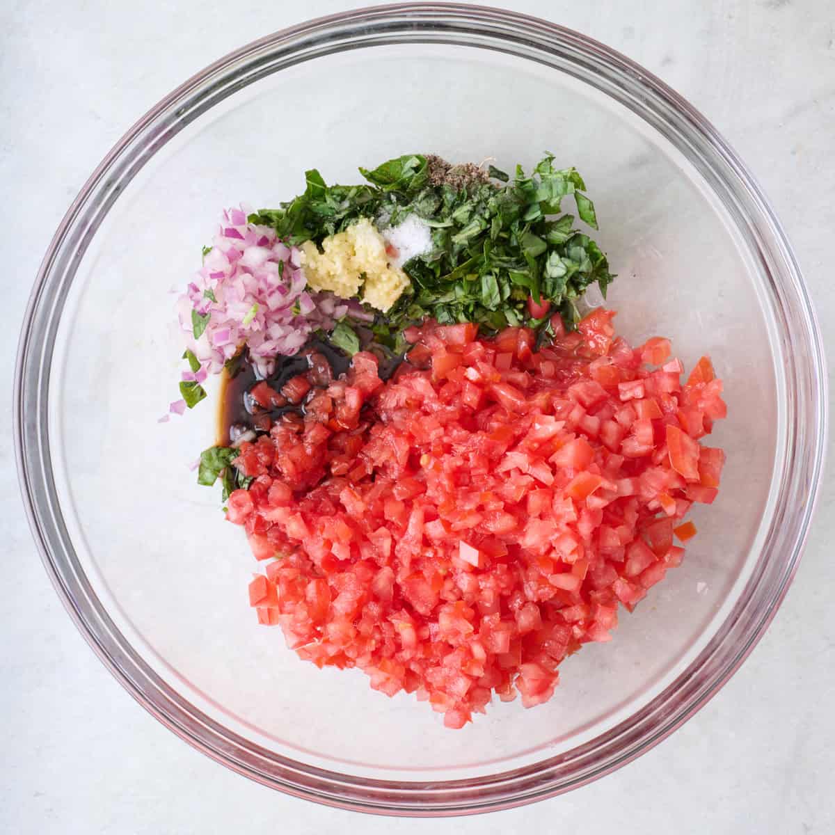 Tomato basil bruschetta ingredients in a mixing bowl.