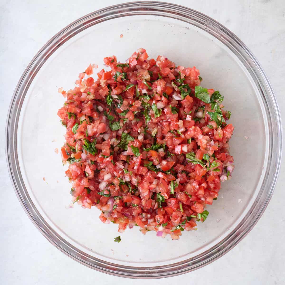 Tomato basil bruschetta in a mixing bowl.