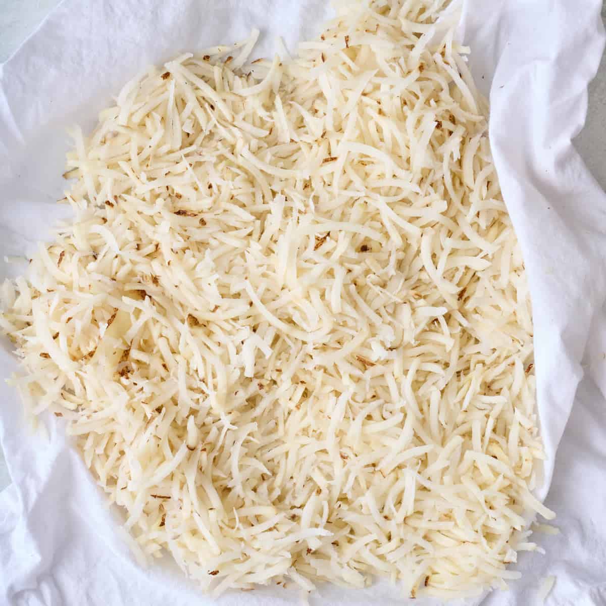 Shredded potatoes drying on a dish towel.