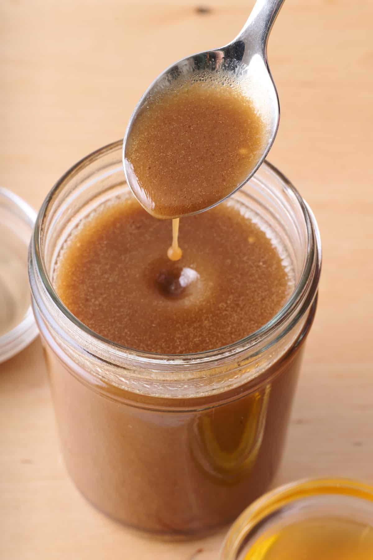 Balsamic vinaigrette in a small mason jar with a spoon drizzling some back into it.