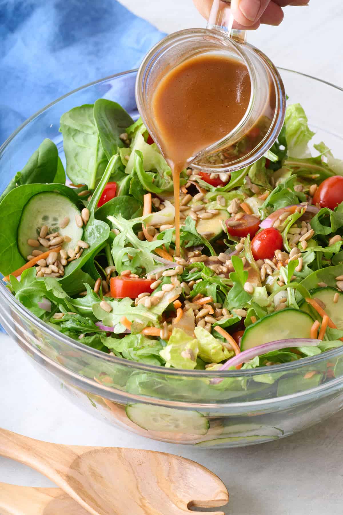 Balsamic vinaigrette dressing being poured over a fresh green salad.