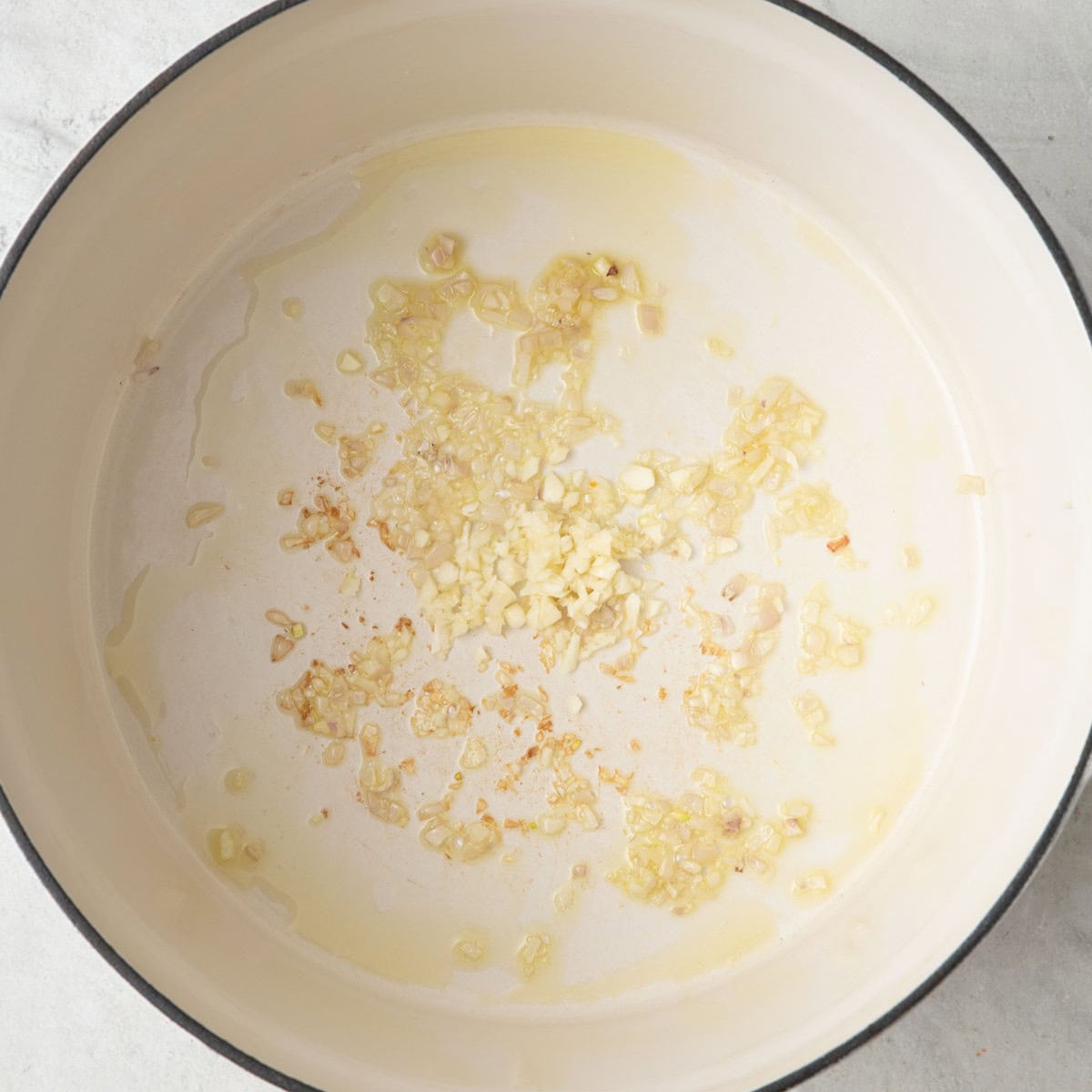 Shallots in a Dutch oven after sauteeing with fresh garlic added.