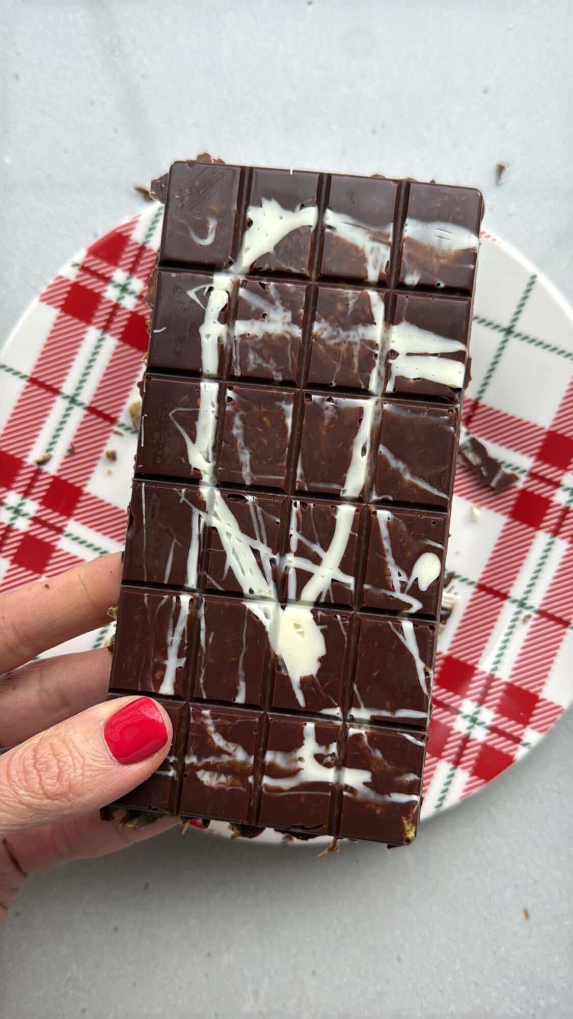 Homemade Dubai Chocolate Bar recipe being hold over a holiday plate by a hand.