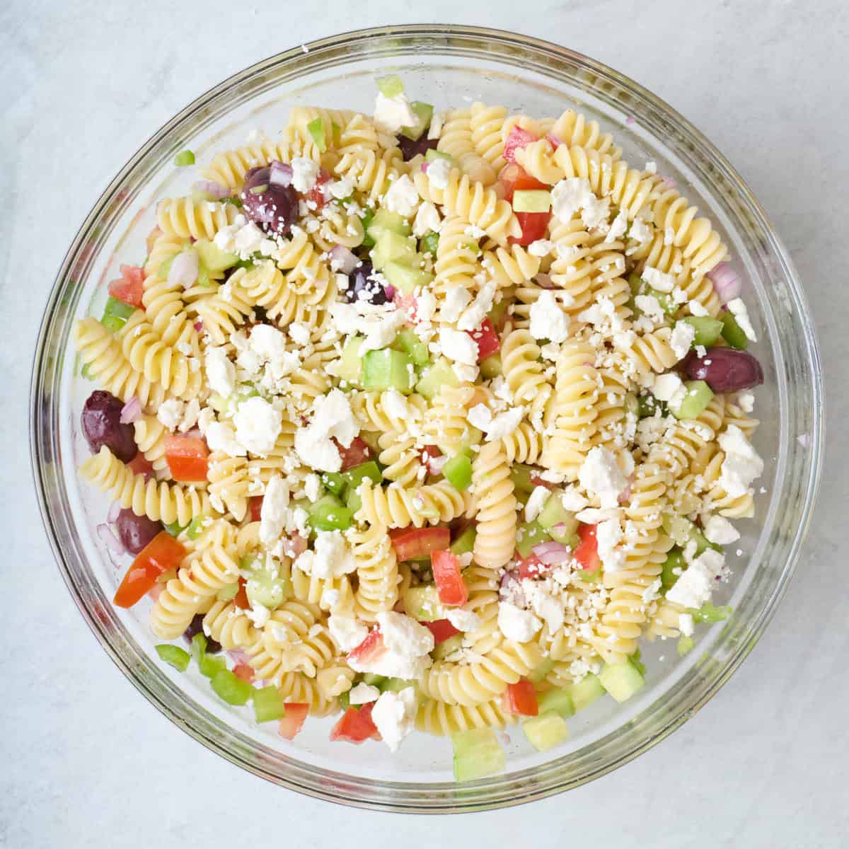 Greek pasta salad in a large glass mixing bowl.