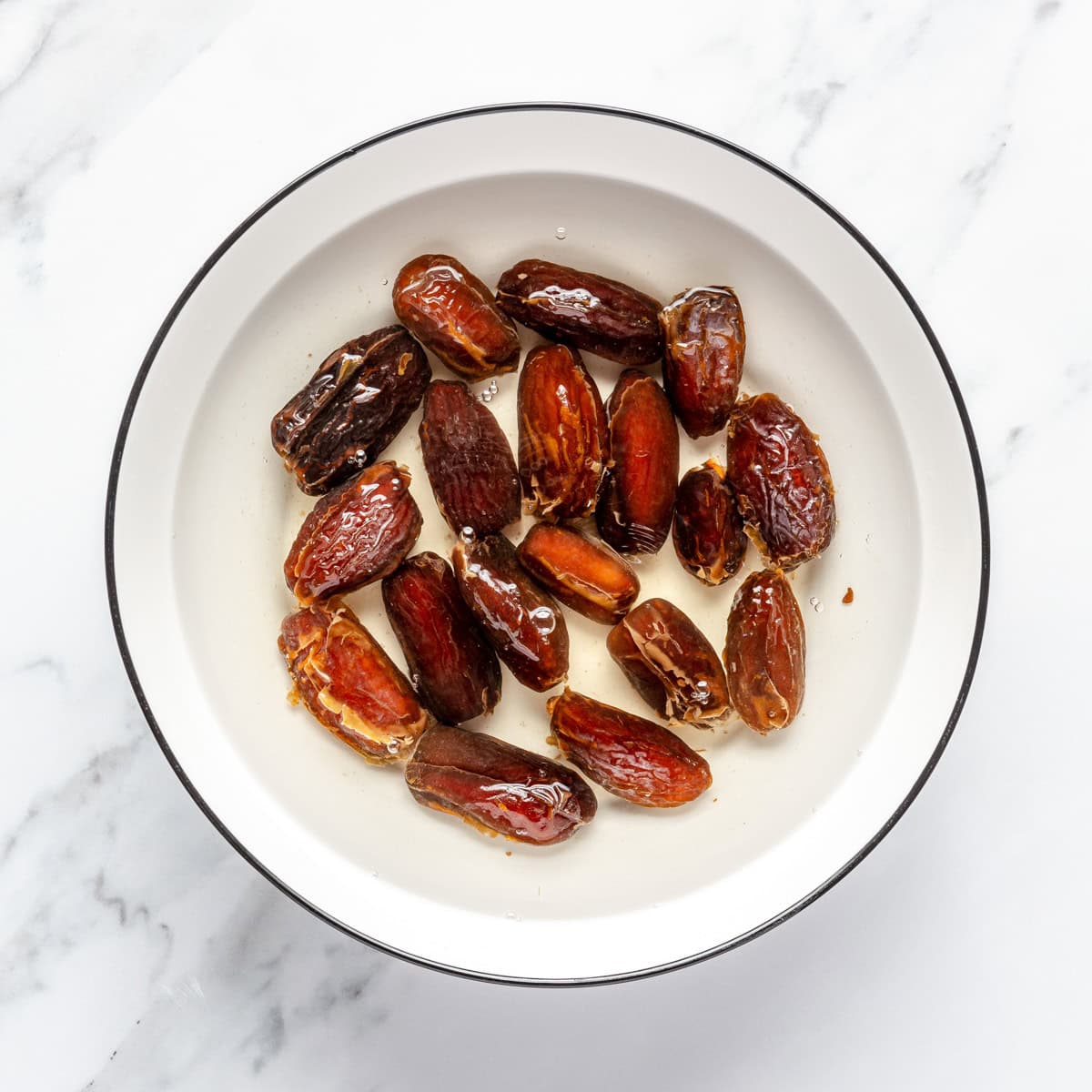 Dates covered with water in a bowl.