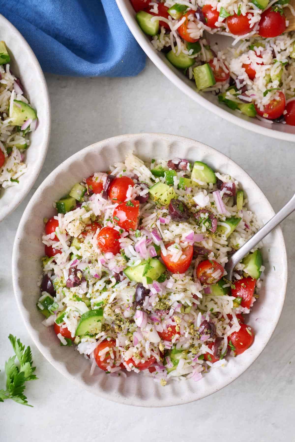 Mediterranean rice salad in a small bowl with a wood spoon dipped inside.