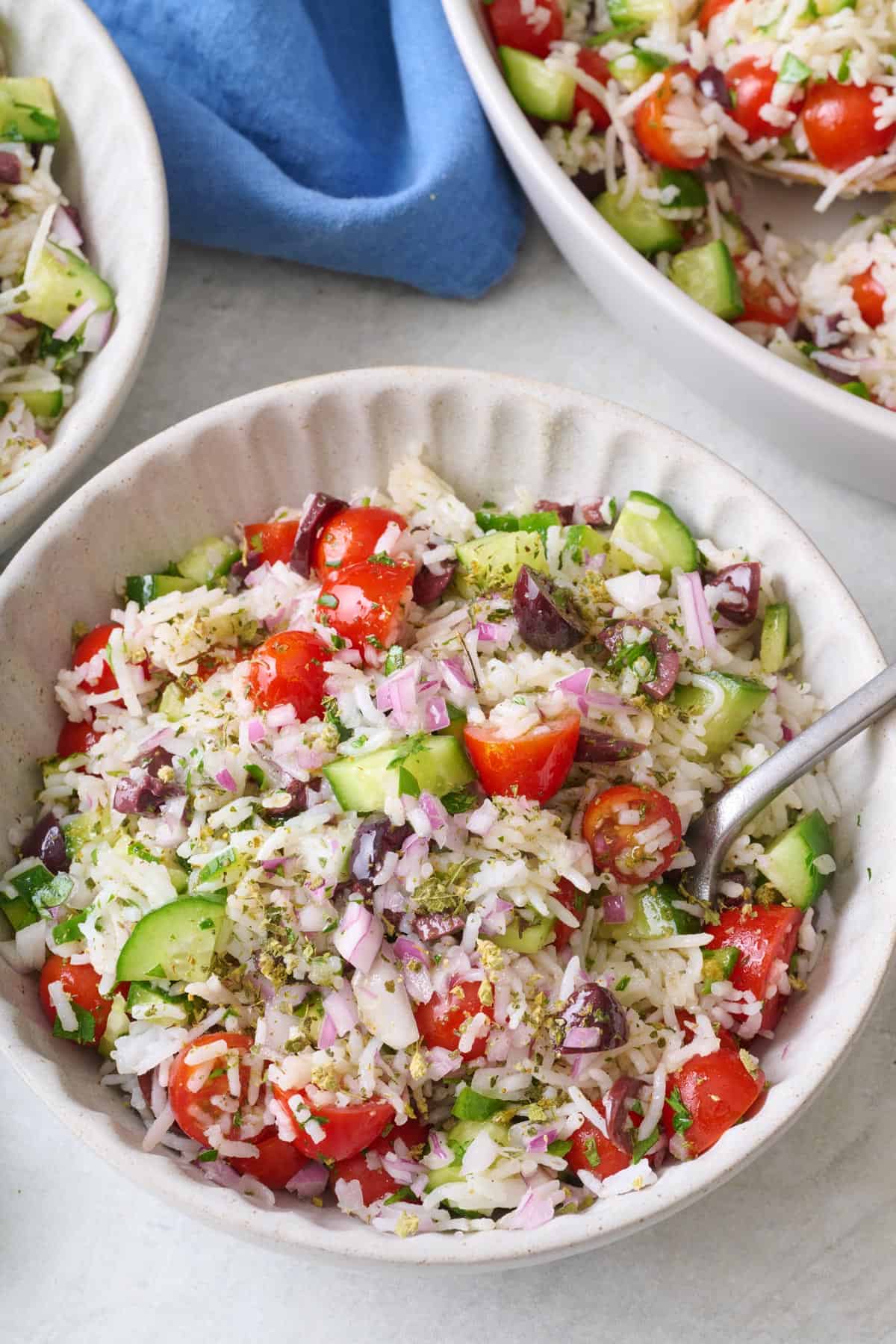 Small bowl of veggie rice salad with tomatoes. cucumbers, and olives.