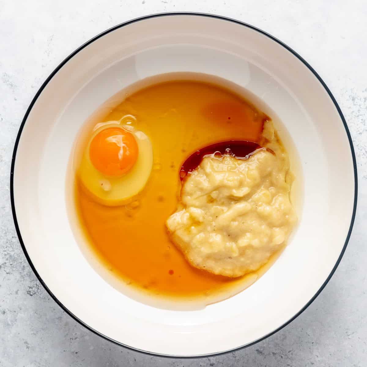 Banana, maple syrup, oil, egg, and vanilla in a bowl before combining.