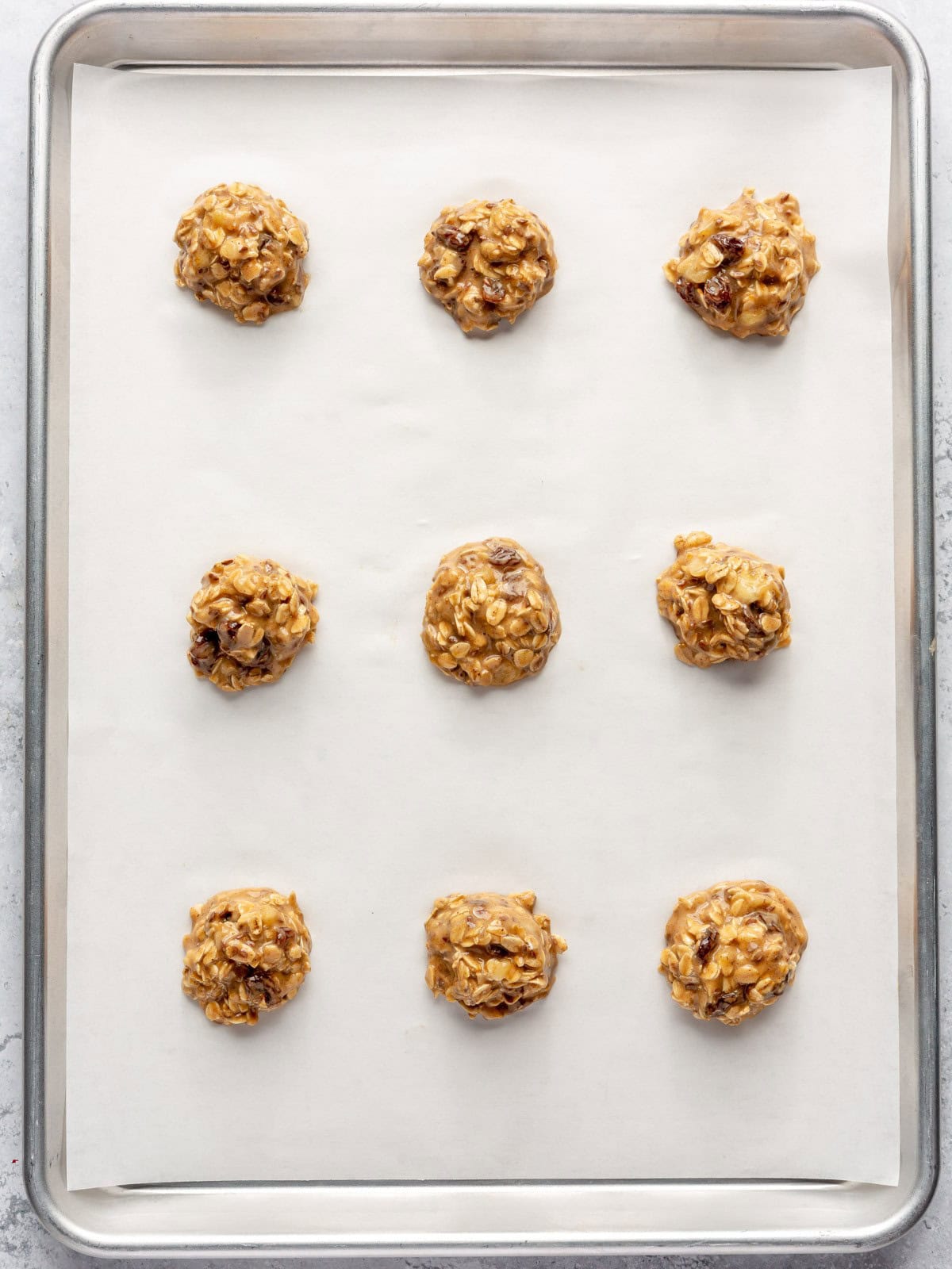 Scooped cookie dough on a parchment lined baking sheet before baking.