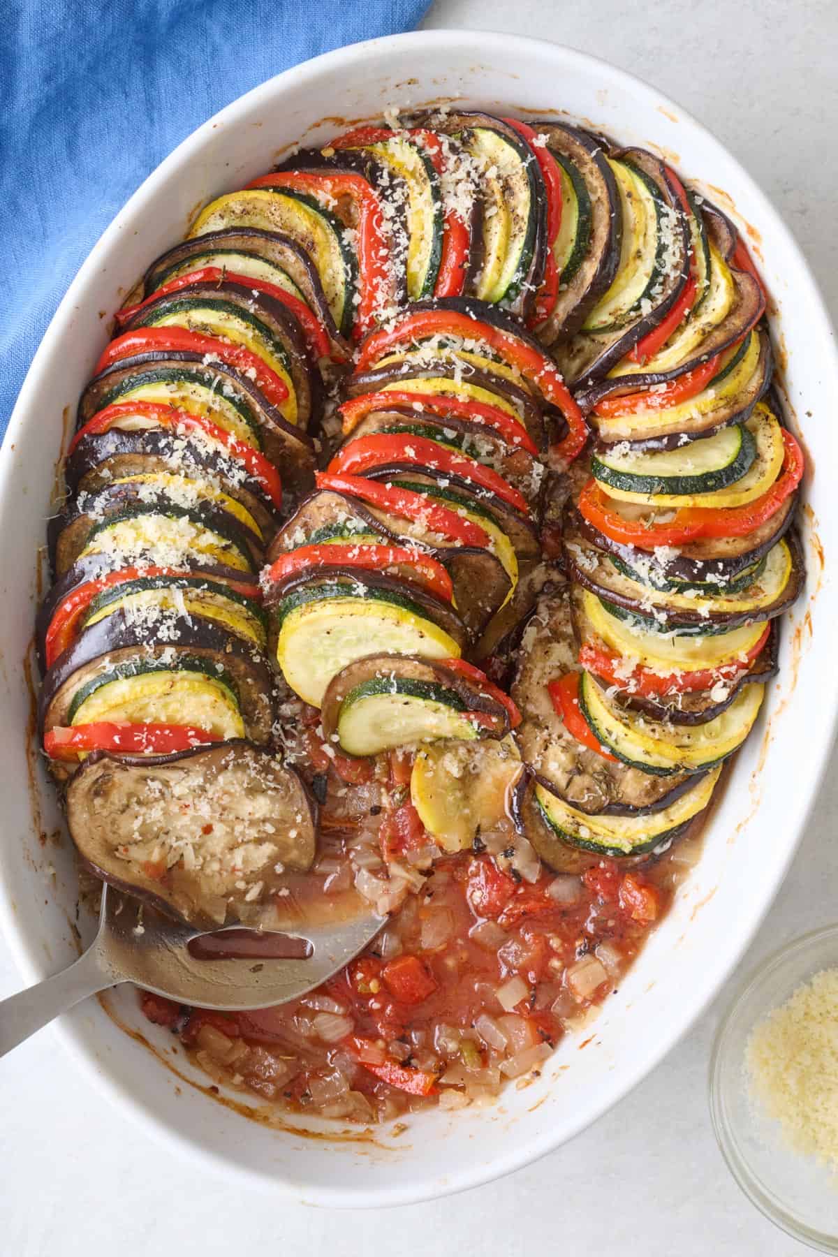 Baking dish of ratatouille with serving removed to show tomato sauce mixture on the bottom of pan.