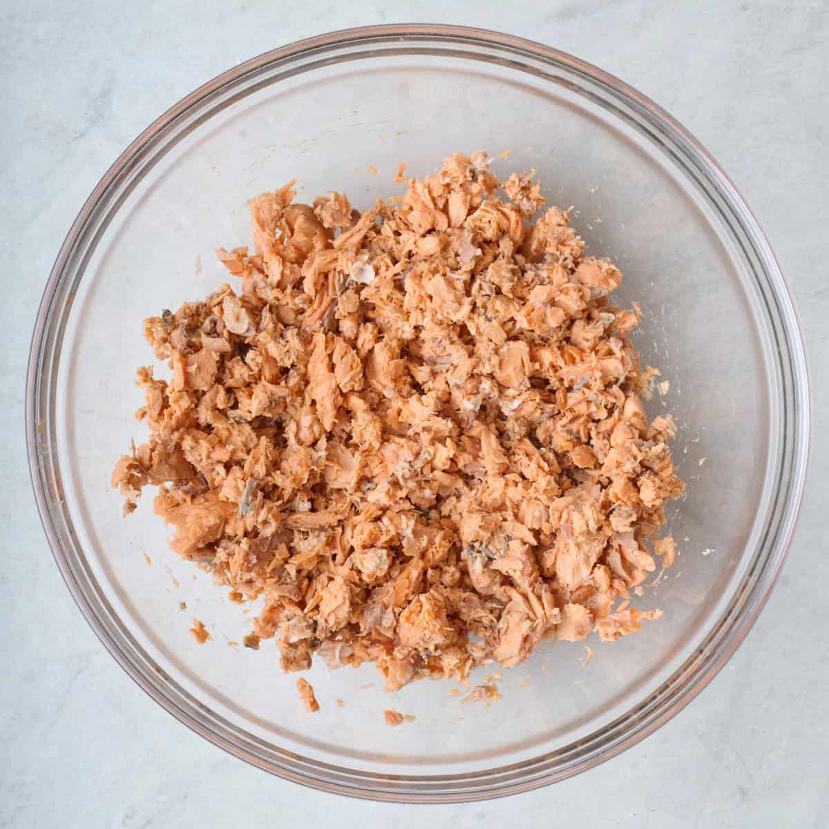 Canned salmon in a bowl after flaking into small chunks.