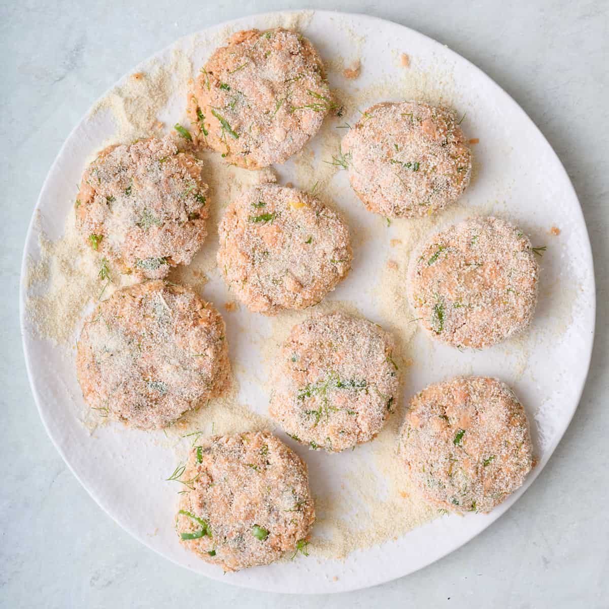 Fish patties coated in breadcrumbs on a plate ready for cooking.