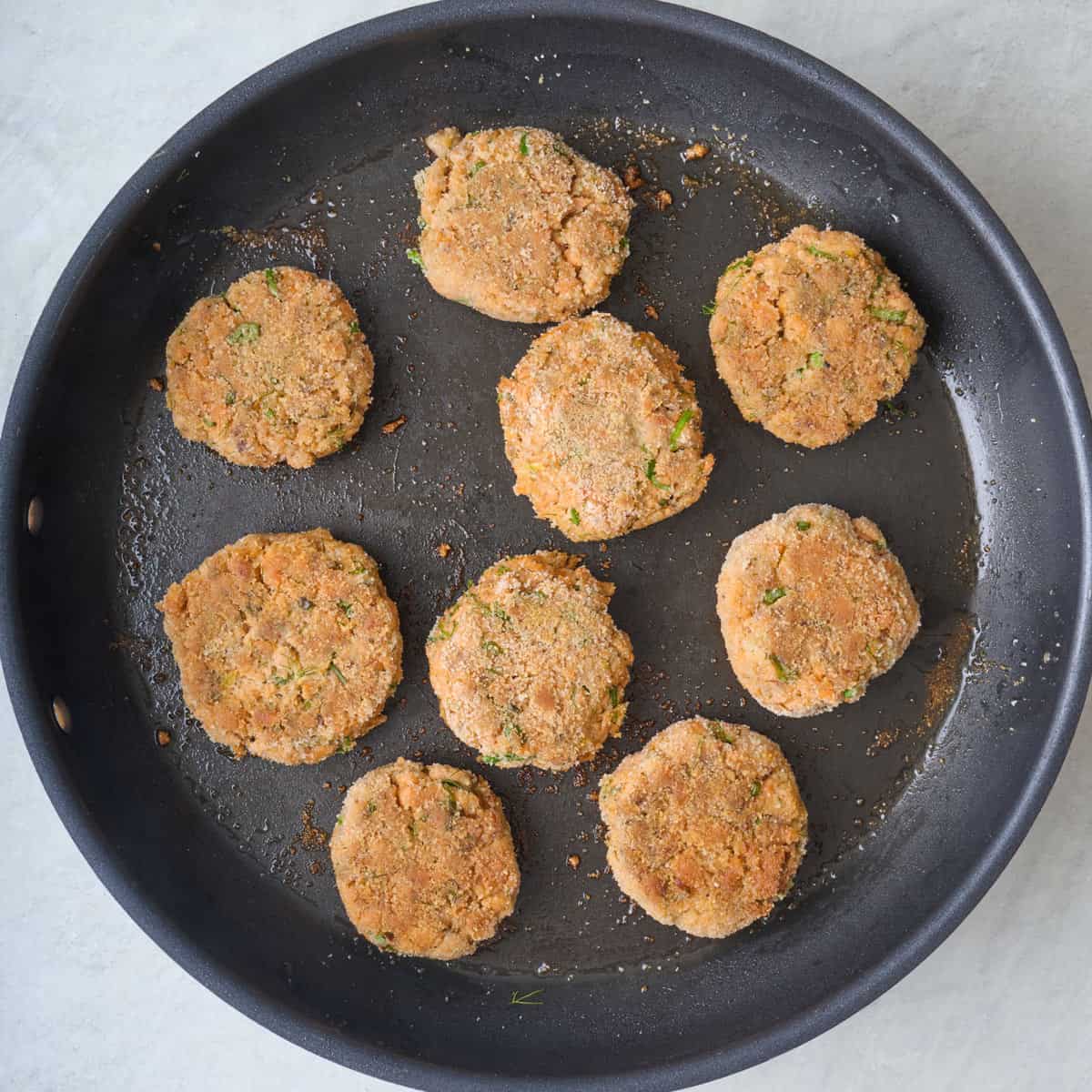 Fish patties after flipping to show golden brown crust.