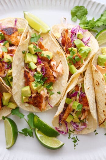 salmon tacos on a plate with lime wedges