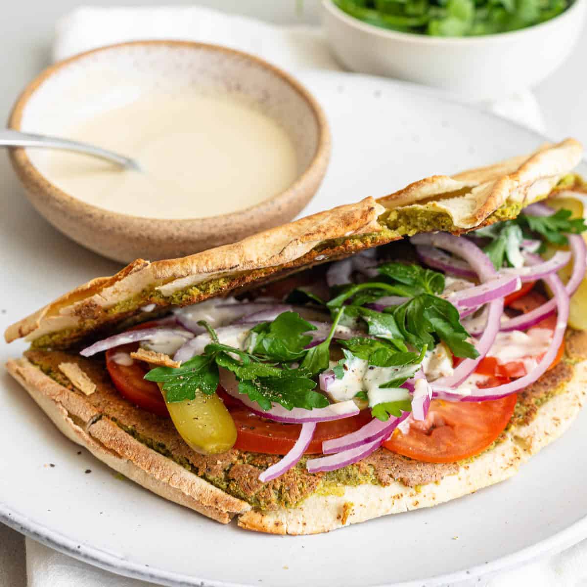 Smash falafel pita folded in half with toppings and tahini sauce.