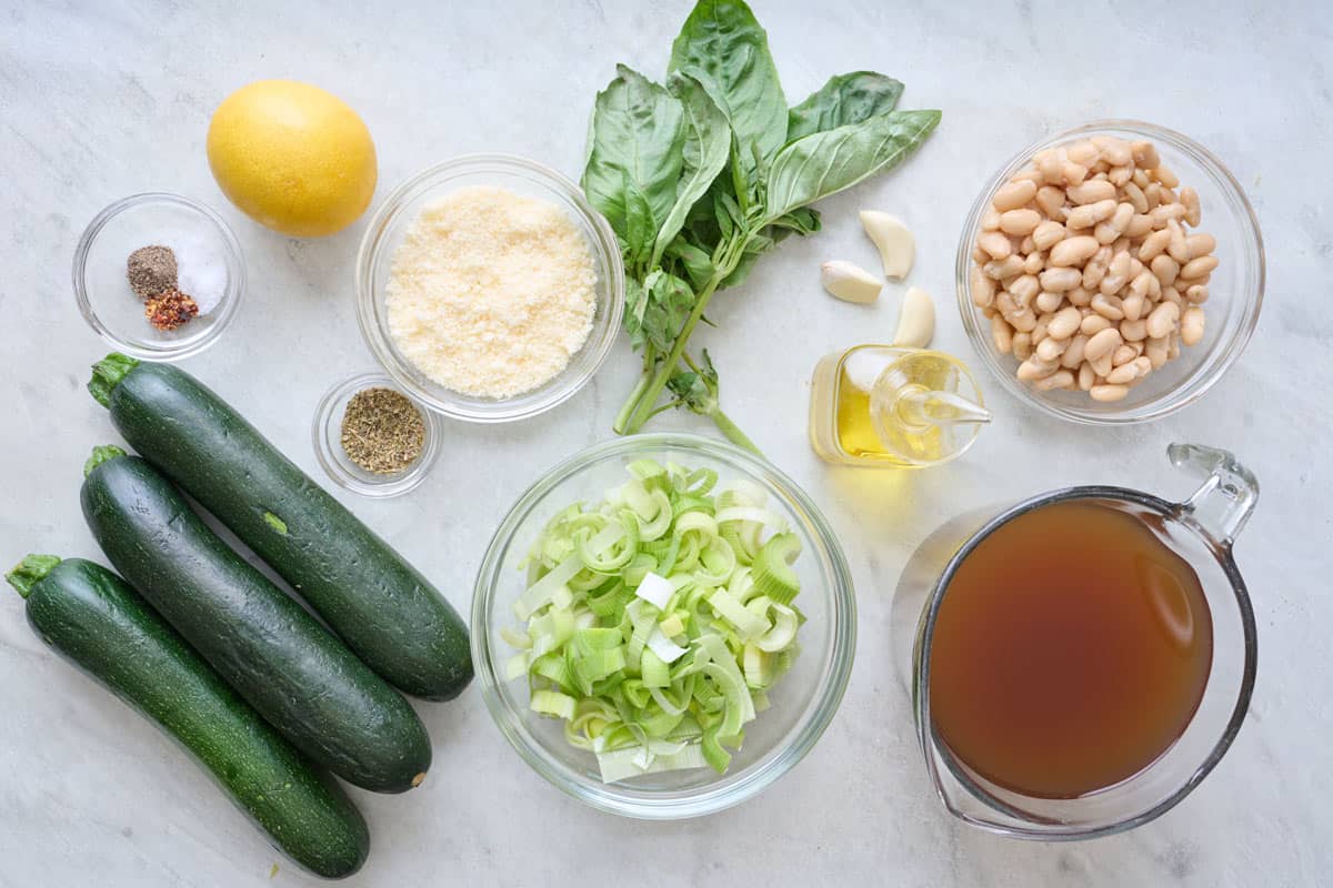 Zucchini soup ingredients on a marble countertop.