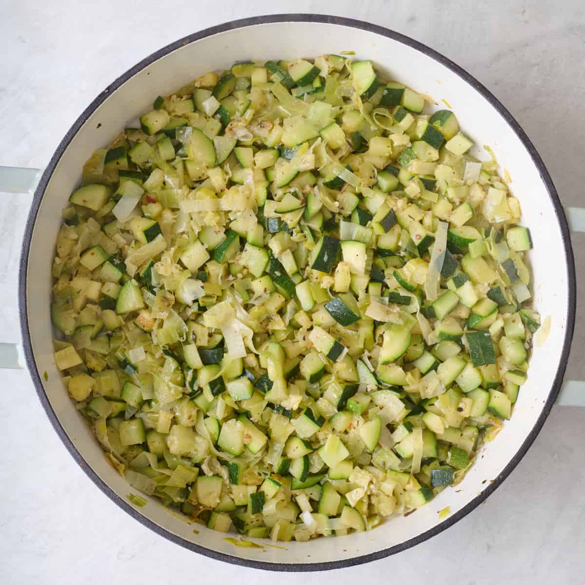 Cooked zucchini, leeks, and seasoning in a Dutch oven.